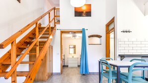 Una escalera conduce a una habitación con comedor, vista al atardecer y pared de azulejos blancos.