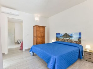 Ein Schlafzimmer mit einem Bett, einem Kleiderschrank, einem Gemälde und einem Nachttisch.