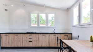 A modern kitchen with wooden cabinets, a black countertop, and a dining area with a table and chairs.