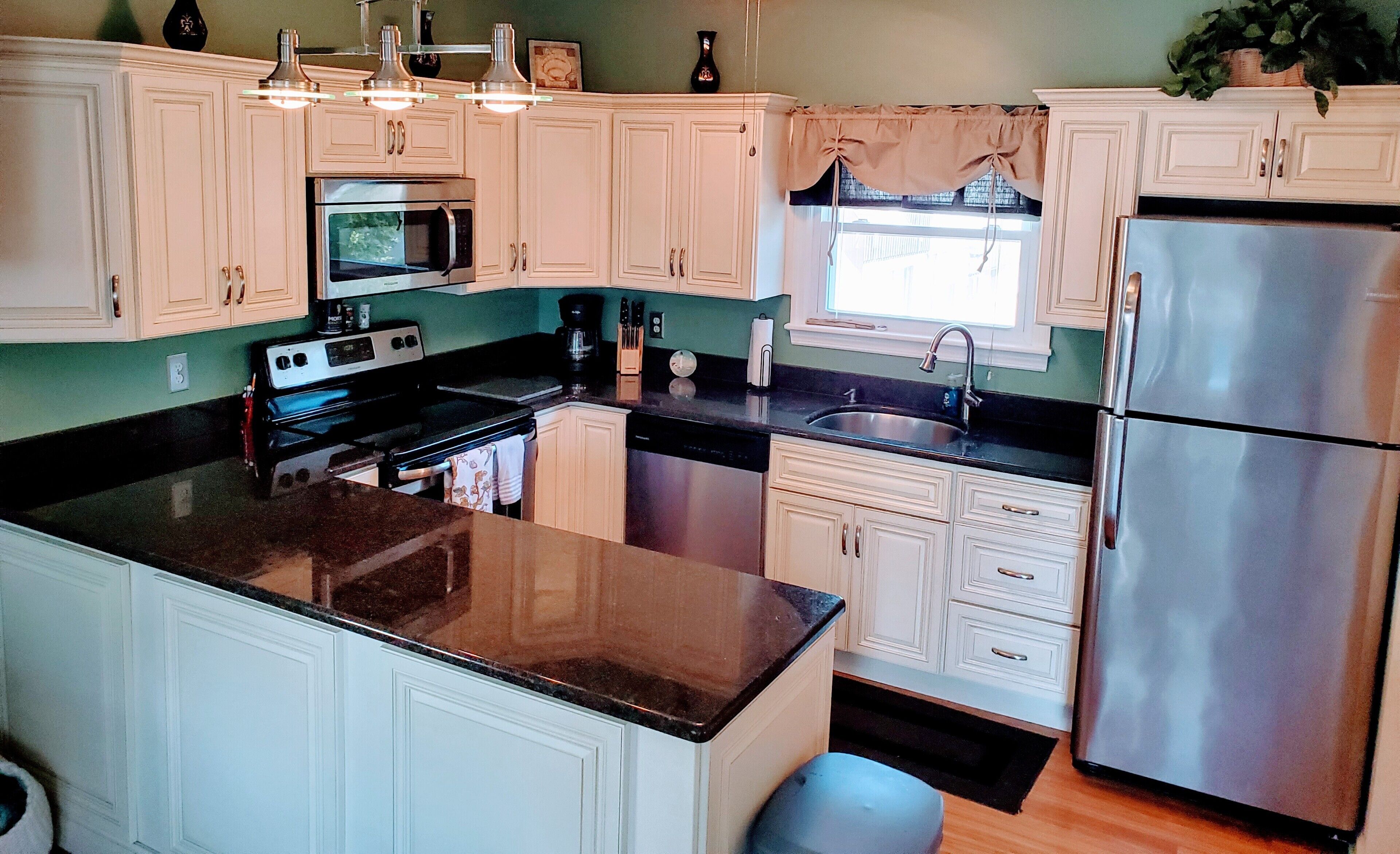 A modern kitchen with white cabinetry, stainless steel appliances, and a granite countertop.
