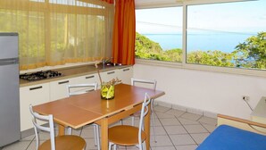 A compact kitchen with a dining area, a view of the sea, and a small sleeping area. - Nice apartment for 4 people with WIFI, TV and terrace (Portoferraio)