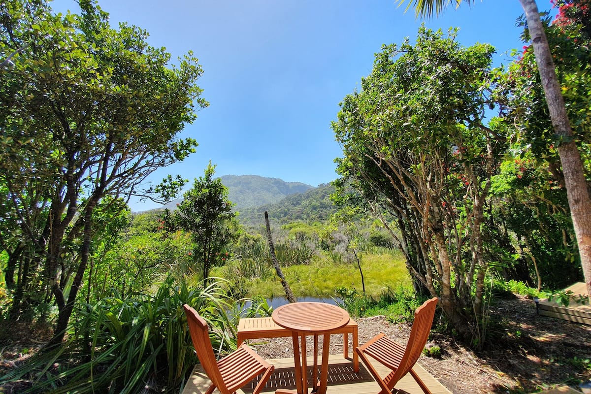 Una mesa y sillas de madera en un jardín con vistas a una cadena montañosa.