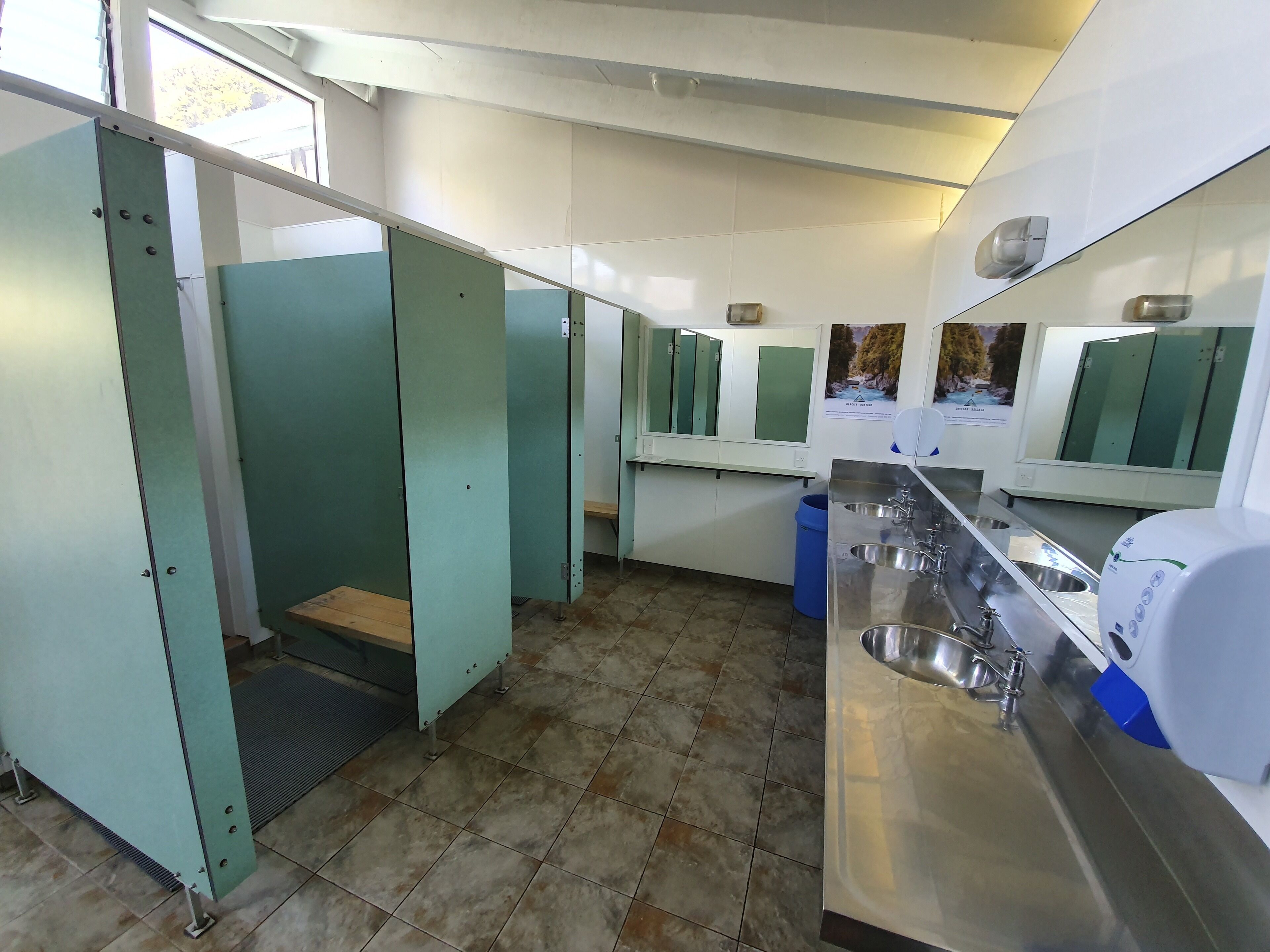 A public restroom with individual stalls, a sink area, and a trash bin.