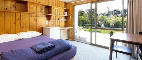 Un dormitorio con cama, escritorio y vistas al exterior.