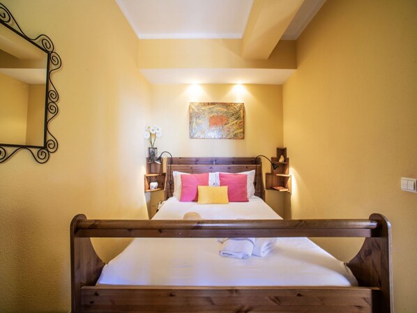 Relax in a cozy space with a comfortable bed, a wall-mounted mirror, and a decorative artwork.