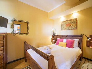 Relax in a cozy space with a comfortable bed, flat-screen TV, and a nightstand with a lamp and vase of flowers.