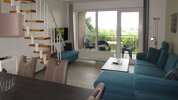 Een moderne woonkamer met een trap, een bank, een eettafel en uitzicht op de omgeving.
