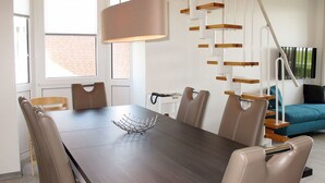 Een moderne eetruimte met een donker houten tafel, lederen stoelen en een metalen decoratiestuk.