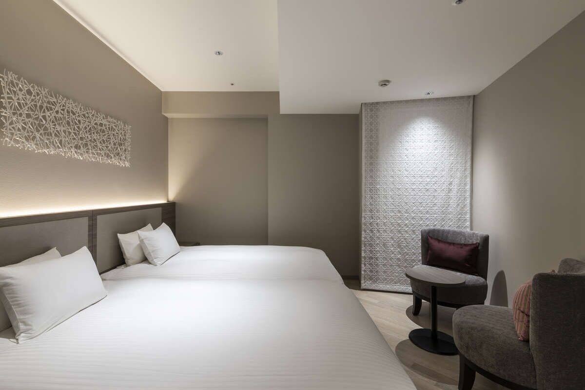 A modern hotel room with a large bed, a small round table, and a chair.