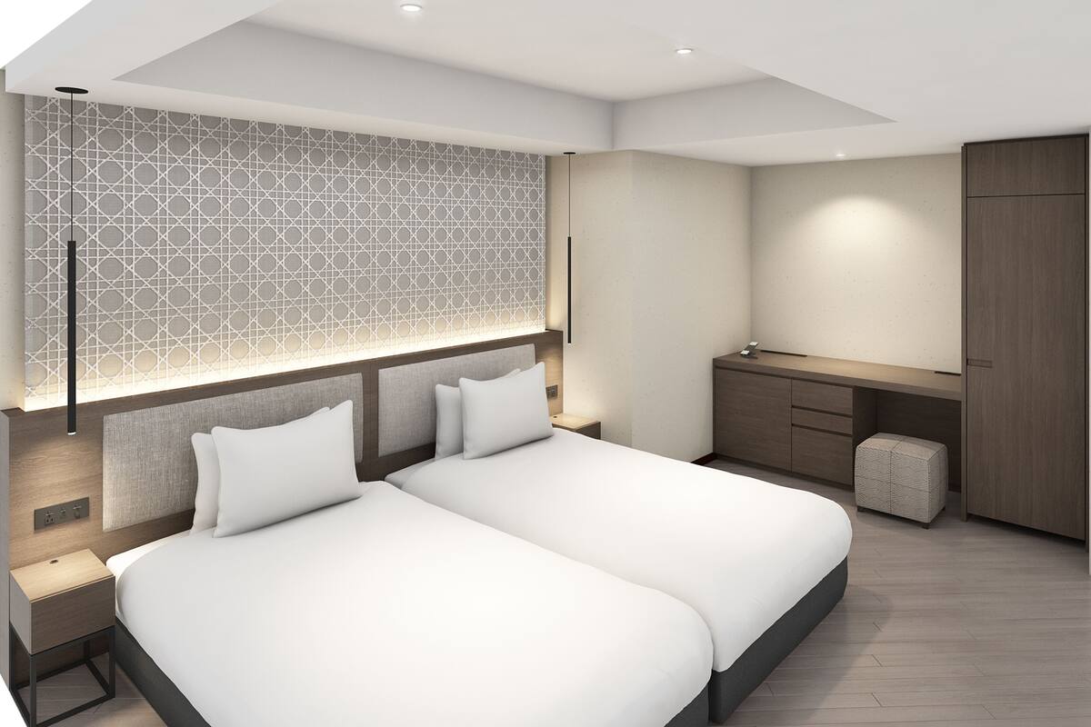 A modern bedroom with two beds, a desk, and a wardrobe.