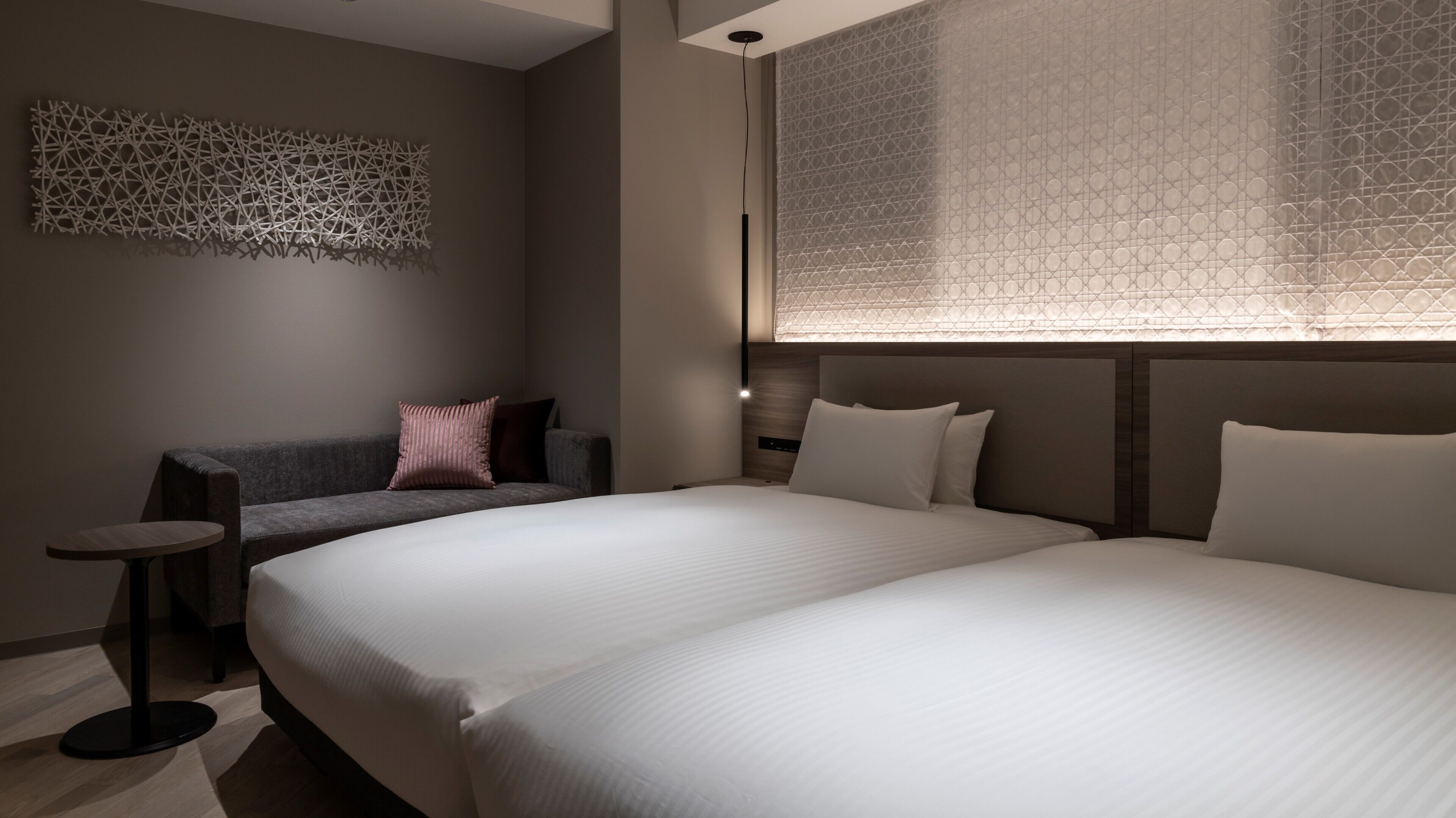 Una habitación de hotel moderna con una cama grande, un sofá, una mesita y un adorno en la pared.