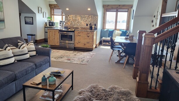 A spacious living area with a sofa, coffee table, rug, and a staircase leading to a dining area. - LUXURY Loft on Multi-Million 4 acre Estate in charming, Swiss town (Midway)