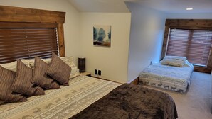 A bedroom with a large bed, a smaller bed, wooden headboard, a painting on the wall, and a window with blinds. - LUXURY Loft on Multi-Million 4 acre Estate in charming, Swiss town (Midway)