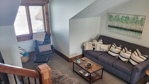 A cozy living room with a grey sofa, a black chair, a wooden coffee table, and a fluffy rug. - LUXURY Loft on Multi-Million 4 acre Estate in charming, Swiss town (Midway)