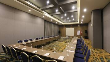 A conference room with a long table, chairs, and a projector screen.