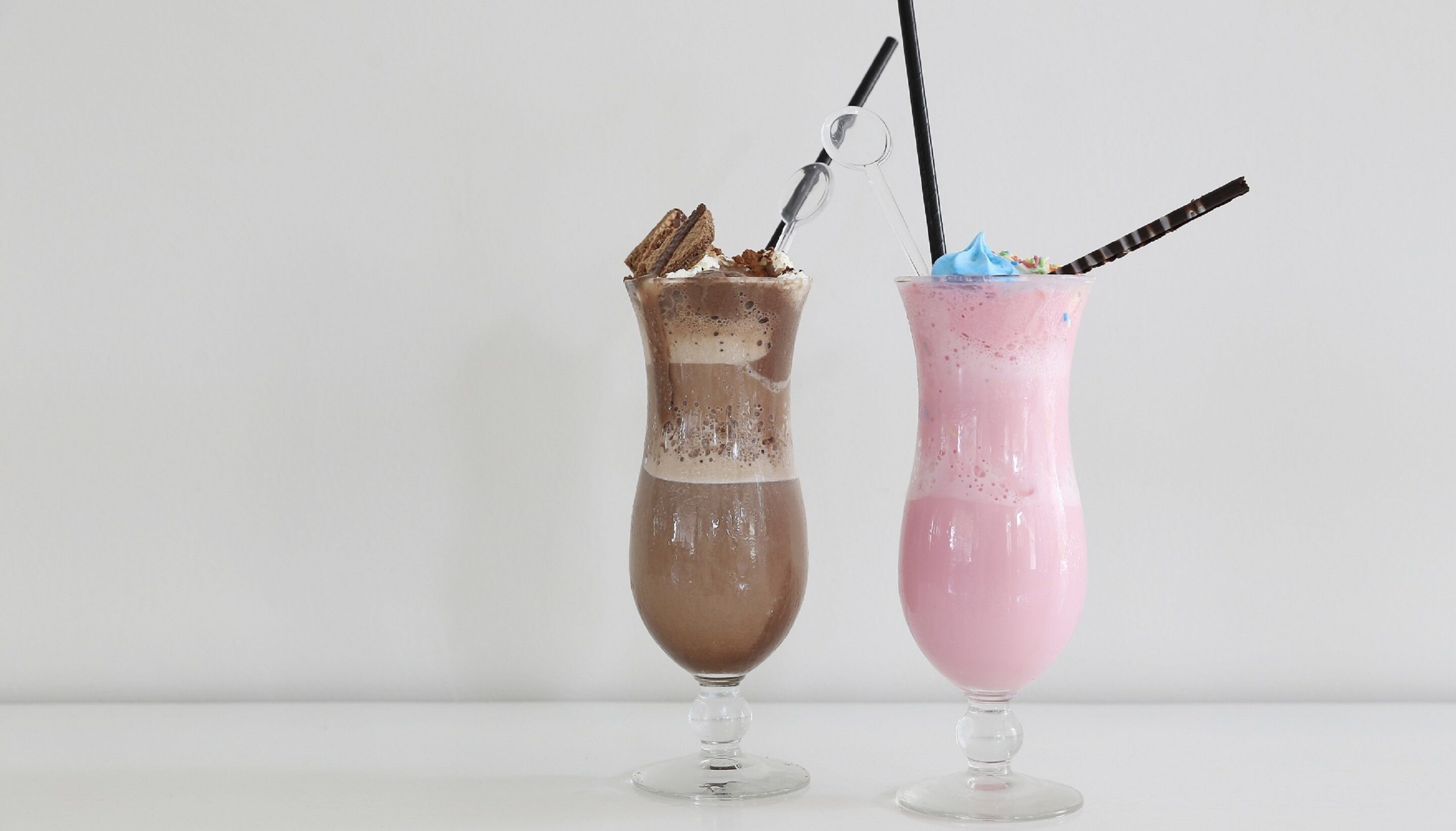 Deux boissons servies dans des verres transparents, accompagnées de cuillères.