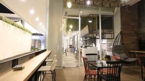 Un restaurant moderne avec un long comptoir, des tables et des chaises en bois. Un escalier mène à un niveau supérieur.