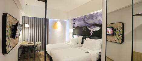 A hotel room with a bed, desk, chair, and a wall-mounted TV.