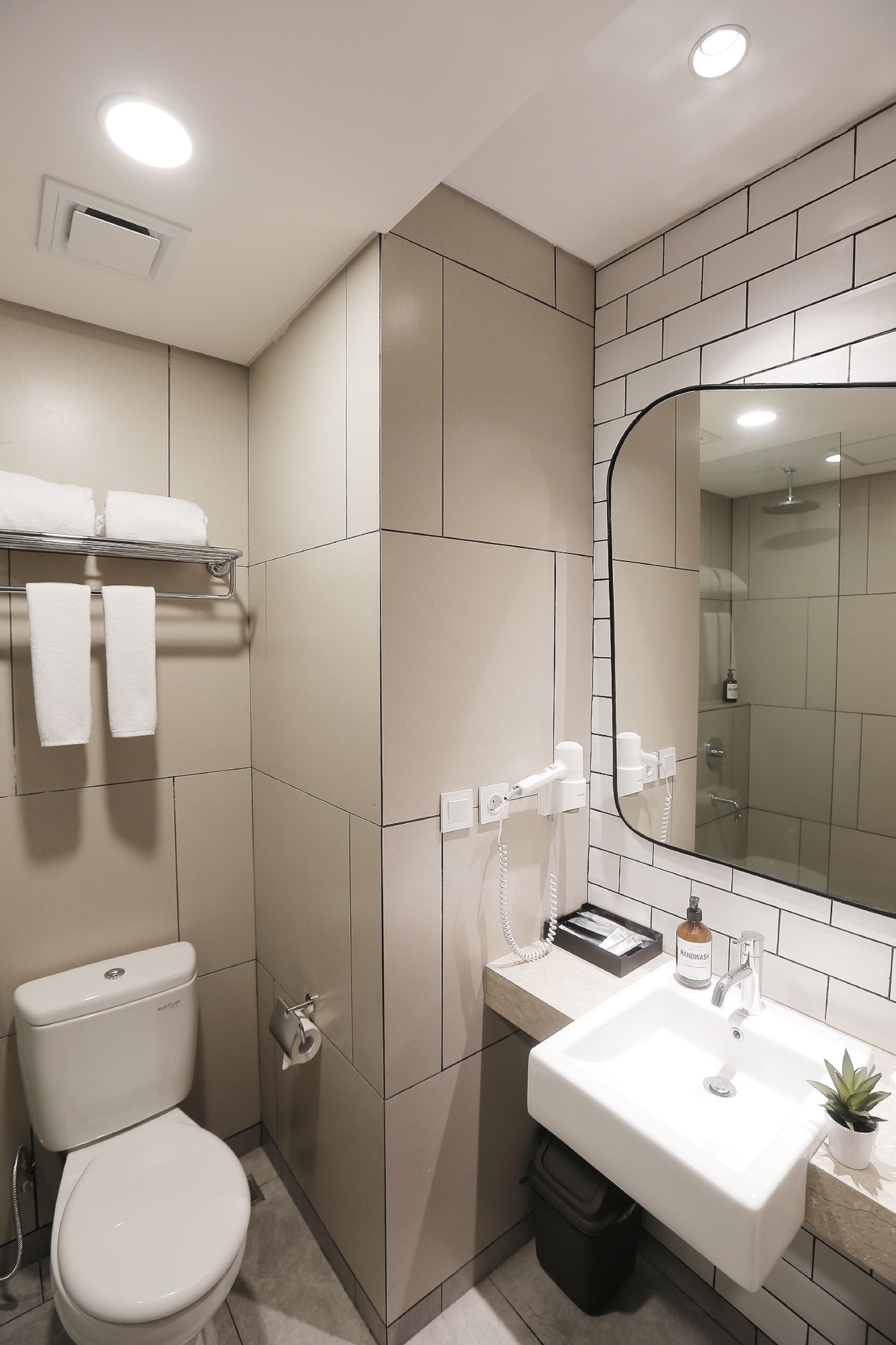 Et moderne badeværelse med toilet, vask og brusebad.
