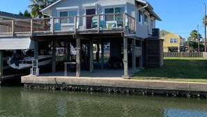 Una casa frente al agua con balcón, muelle y un bote.