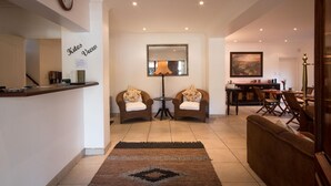A spacious living area with a sofa, two armchairs, a dining table, and a lamp.