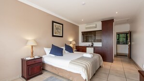 A bedroom with a bed, nightstands, a desk, and an air conditioning unit.