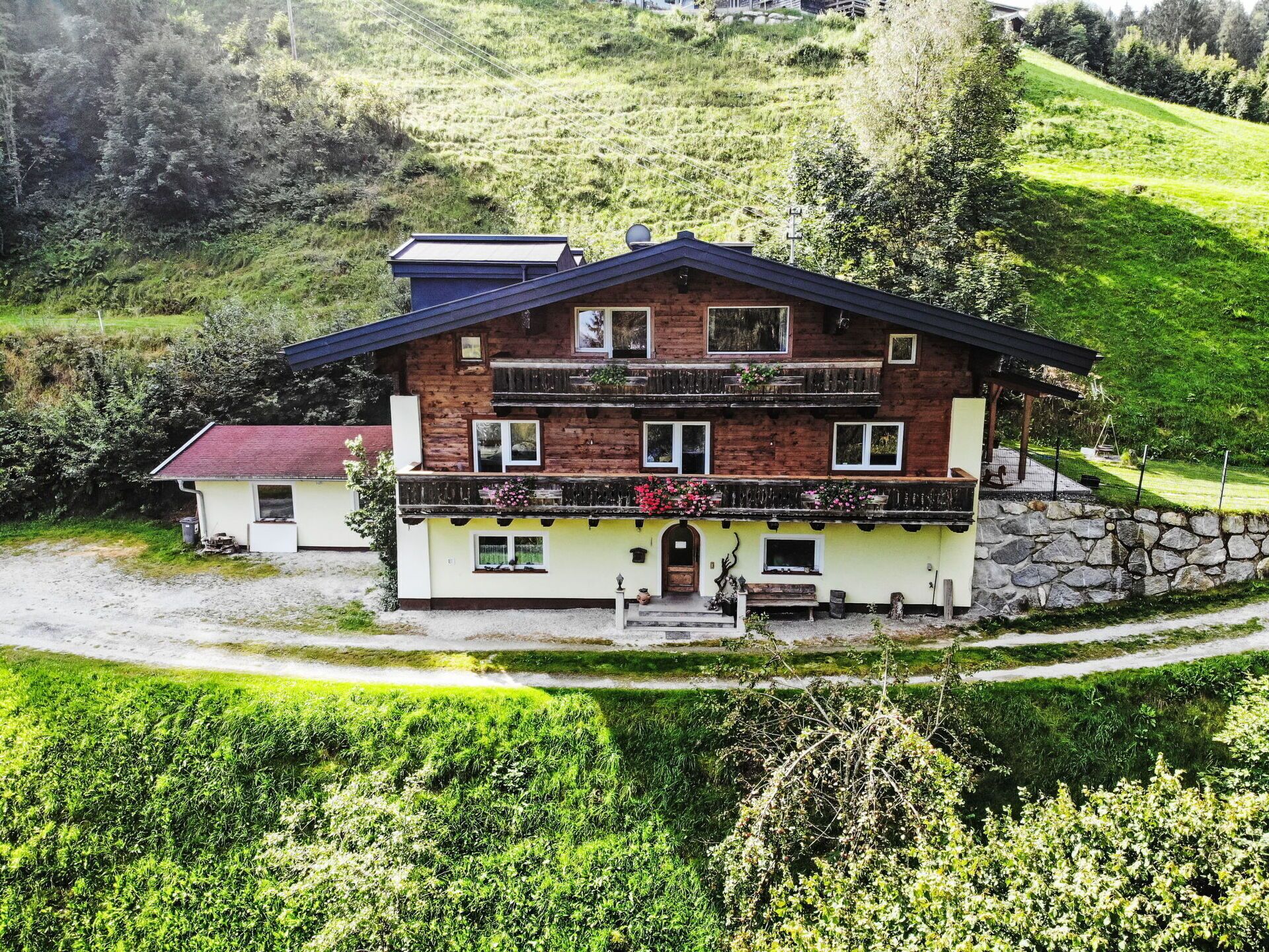 A two-story chalet with a stone foundation, a balcony with flower boxes, and a small porch area.