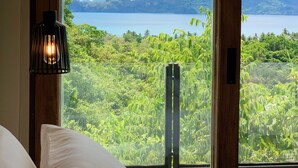 Una habitación con un ventanal que ofrece vistas a un lago, montañas y vegetación exuberante.