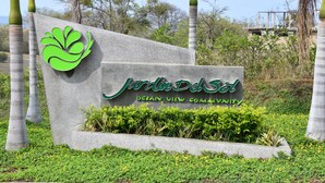 Señal de 'Jardín Del Sol' con logotipo verde e indicación de que forma parte de la 'Ocean View Community'.