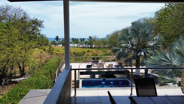 Zona de piscina con sillas de descanso y vista al océano.