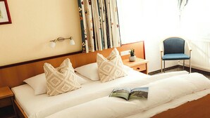A double bed with patterned pillows, a bedside table with a lamp, a chair, and a window with curtains. - Lovely apartment for 6 guests with WIFI, TV and terrace (Thurmbach)