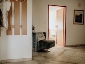 A hallway with a dark-colored sofa, a small table with a plant, a door leading to another room, and a framed picture on the wall. - Cosy apartment for 6 people with WIFI, TV and terrace (Thurmbach)