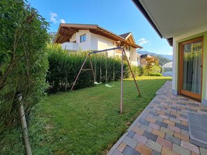 A residential property with a well-maintained lawn, a swing set, and a brick pathway leading to a door. - Nice apartment for 6 guests with WIFI, TV and terrace (Thurmbach)