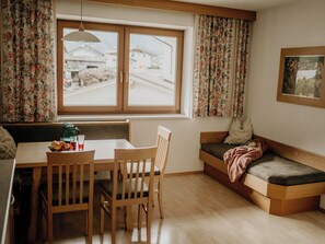 A cozy room with a wooden table, chairs, a bench, and a window with curtains. - Lovely apartment for 3 guests with WIFI, TV and balcony (Thurmbach)