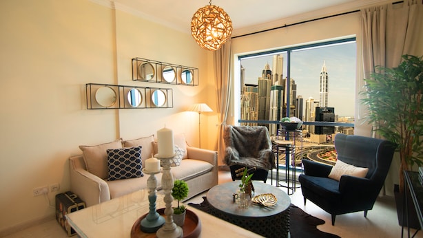 Una sala de estar moderna con vista a la ciudad, una mesa redonda, un sofá y un sillón.