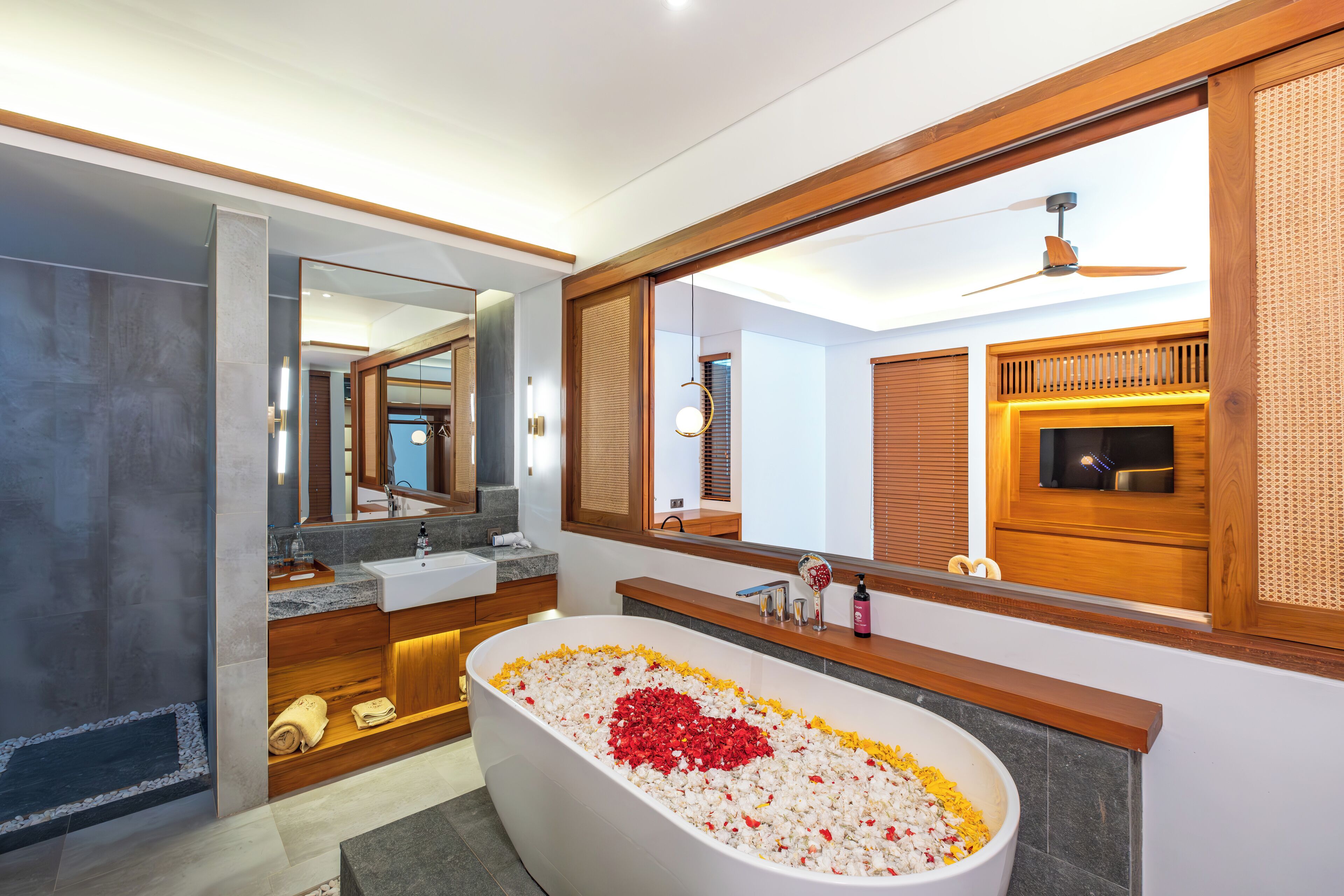 A modern bathroom with a large bathtub, wooden vanity, and a large mirror.