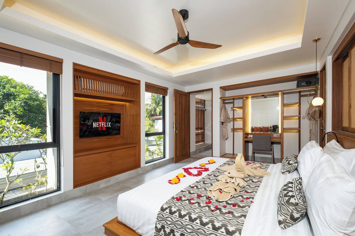 Une chambre d’hôtel moderne avec un grand lit, un bureau et un téléviseur fixé au mur.