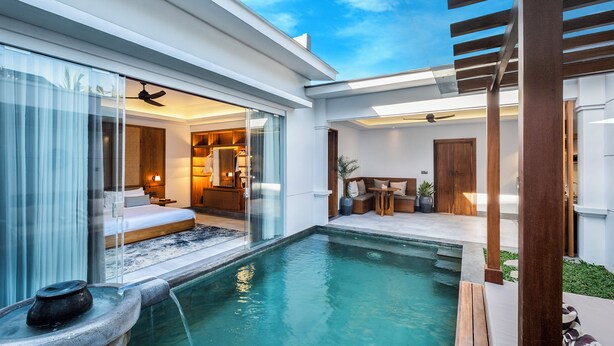 A modern outdoor pool area with a glass-enclosed bedroom, wooden deck, and a ceiling fan.