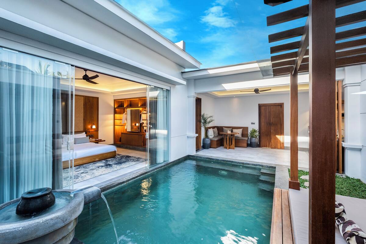 Un espace piscine extérieur moderne doté d’une chambre à coucher entourée de baies vitrées, d’une terrasse en bois et d’un ventilateur de plafond.