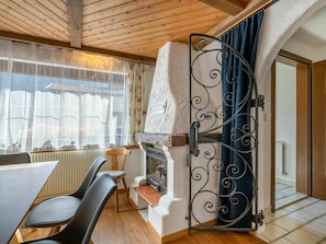 Um quarto aconchegante com lareira, teto de madeira e uma área de refeições com cadeiras e mesa.