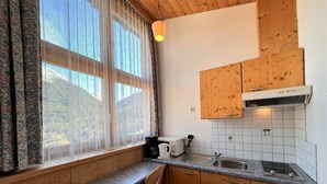 A compact kitchen with wooden cabinets, a granite countertop, a sink, and a window with sheer curtains. - Nice apartment for 2 guests with WIFI, TV and balcony (Solden)