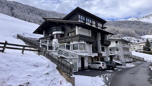 Een meerhoog hotel met een skilift, omringd door met sneeuw bedekte heuvels en een heldere lucht.