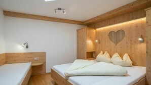 Une pièce dotée d’une lucarne, de murs en bois, d’un lit avec des oreillers, d’une table de chevet et d’une petite étagère.