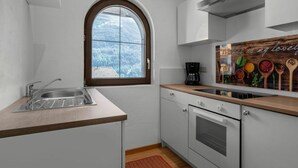 A modern kitchen with a large window, white cabinetry, a built-in oven, and a coffee maker. - Cosy apartment for 6 people with WIFI, TV and balcony (Solden)