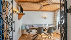 Ein gemütlicher Essbereich mit Holztisch und Stühlen, einer Bank und dekorativen Wandleuchten.