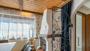 Ein gemütliches Zimmer mit Kamin, Holzbalkendecke und einem Essbereich mit Stühlen und Tisch.