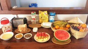 Ein Frühstückstisch mit verschiedenen Speisen, darunter Brot, Obst und Beilagen.