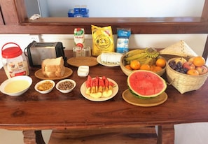 Ett frukostbord med olika sorters mat, inklusive bröd, frukt och pålägg.