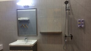 Ein Badezimmer mit Waschbecken, Spiegel, Handtuchhalter, Dusche und Stauraumschrank.