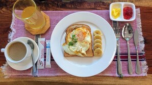 Ein Frühstückstisch mit Toast, Eiern, Bananen und einem Glas Saft.